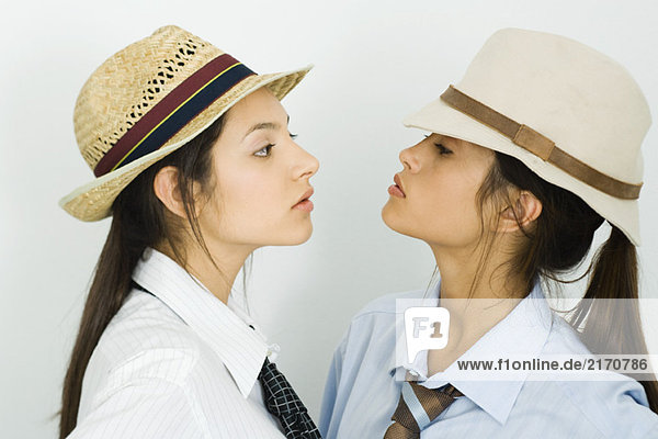 Zwei junge Freundinnen mit Hüten und Krawatten  die sich gegenseitig anschauen