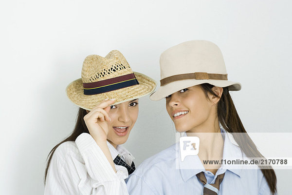 Zwei junge Freundinnen mit Hüten und Krawatten  beide lächelnd vor der Kamera.