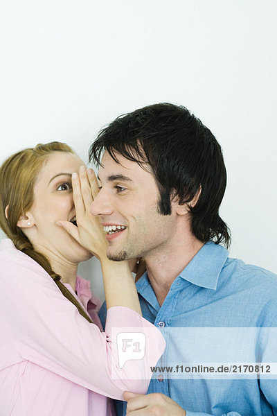 Young woman whispering in man's ear  close-up