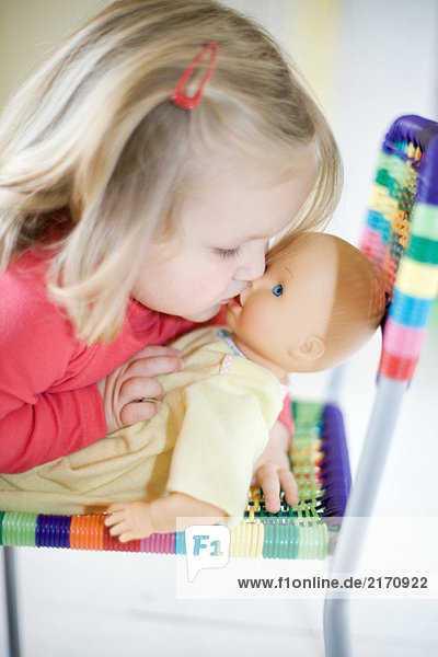 Blonde toddler girl kissing baby doll