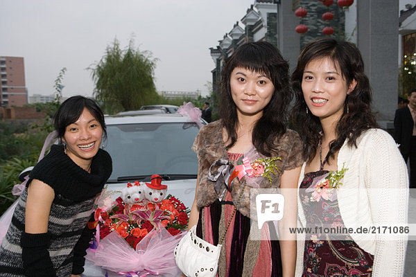 Three female friends standing in front of decorated car  smiling at camera