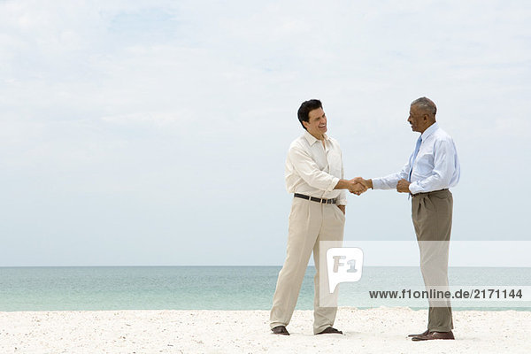 Zwei Geschäftsleute beim Händeschütteln am Strand