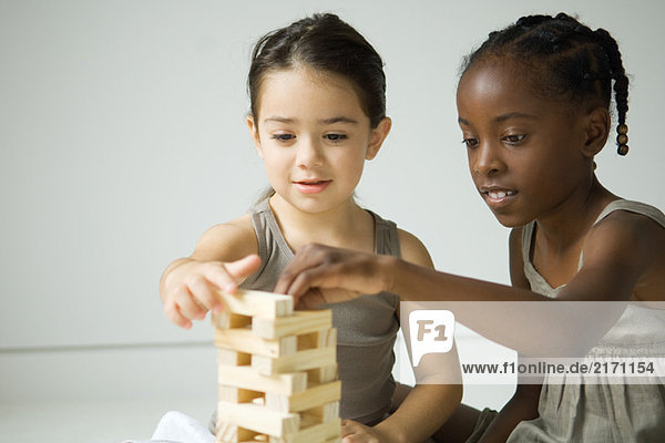 Zwei Mädchen bauen gemeinsam einen Turm mit Blöcken