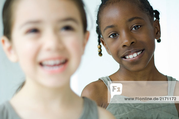 Zwei Mädchen lächeln  eine schaut in die Kamera  selektiver Fokus