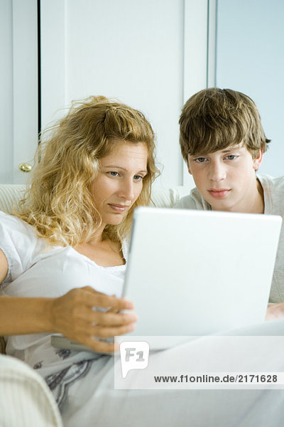 Woman and teen son using laptop
