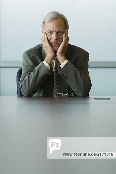 Businessman sitting with head in hands  looking down