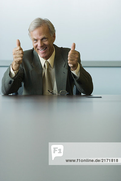 Businessman giving two thumbs up  smiling at camera