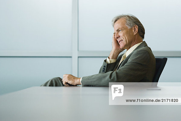 Businessman seated  holding head  looking away