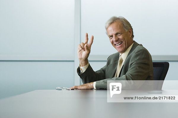 Businessman making peace sign  smiling at camera