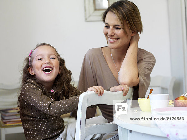 Girl and her mother smiling at breakfast table