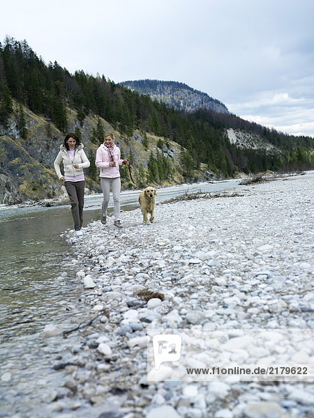 Zwei junge Frauen Joggen mit Hund am Flussufer