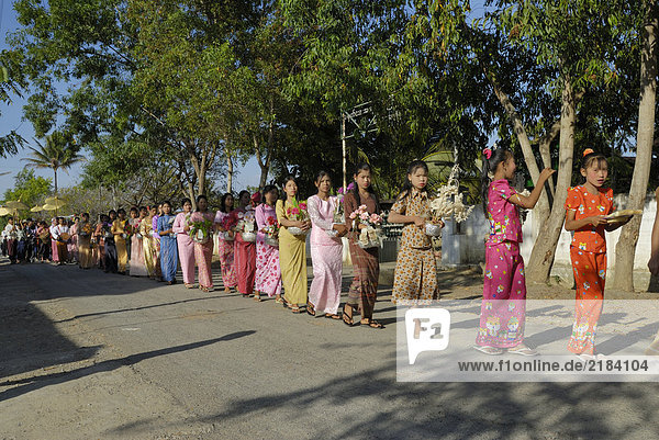 Group of women and girls walking in row with religious offerings  Nyaung Shwe  Inle Lake  Myanmar