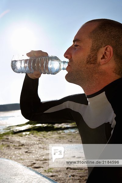 Mann sitzend mit Surfbrett Trinkwasser .