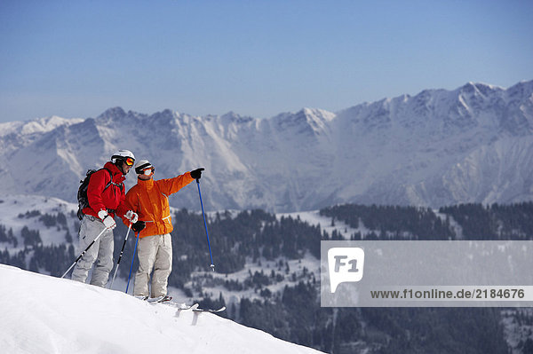 Österreich  Saalbach  zwei männliche Skifahrer auf der Piste  einer davon zeigt