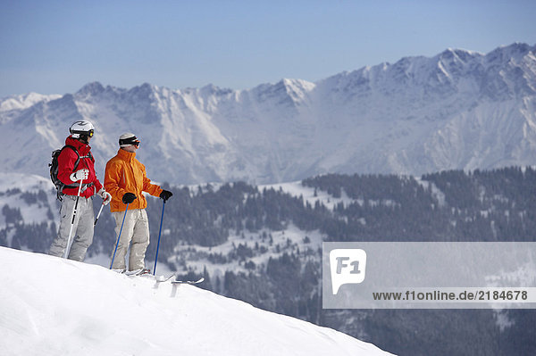 Österreich  Saalbach  zwei männliche Skifahrer auf der Piste mit Blick auf die Berge
