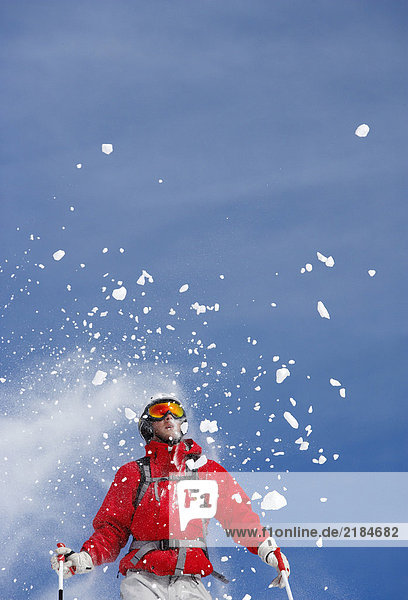 Schneebesprühung über dem männlichen Skifahrer  Tiefblick