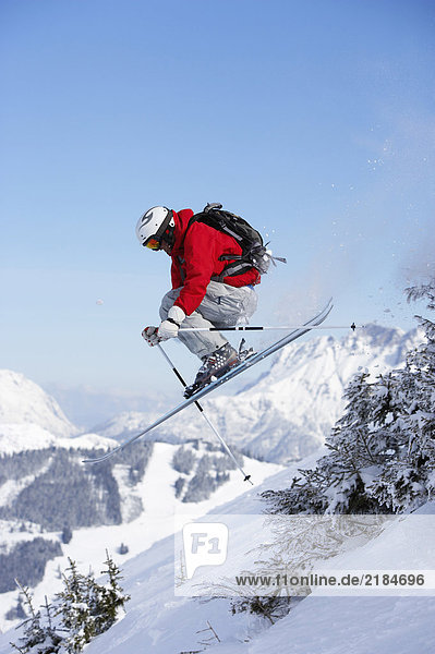 Austria  Saalbach  male skier jumping past trees on slope