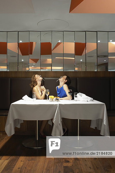 Zwei Frauen in einem Restaurant mit Löffeln auf der Nase.