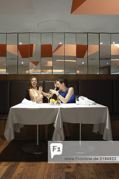 Zwei Frauen in einem Restaurant mit einem Löffel auf der Nase