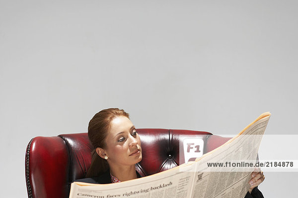 Geschäftsfrau im bequemen Ledersessel mit Zeitung