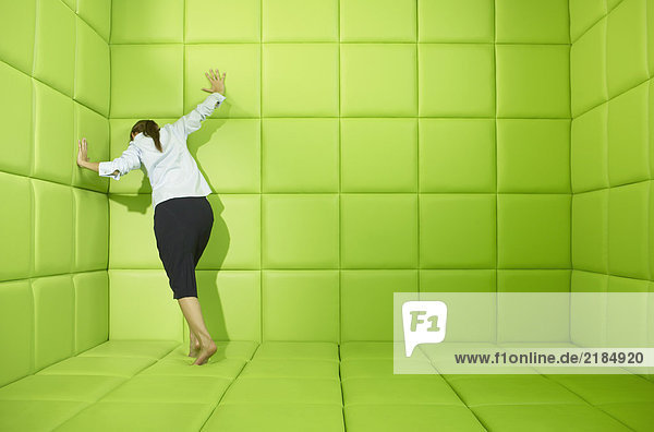 Frau drückt gegen die Wände der grünen Gummizelle