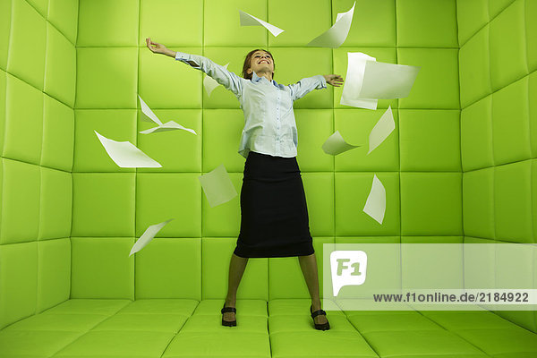 Woman throwing papers around green padded cell
