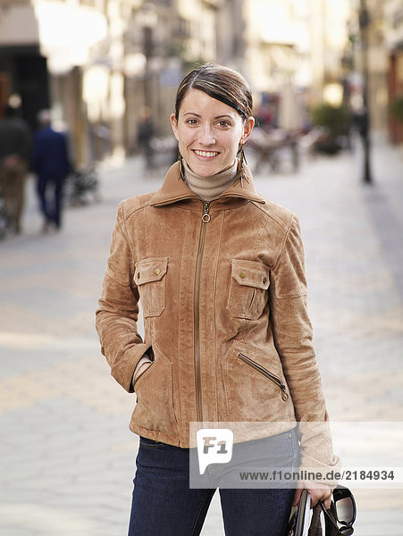 Young woman standing in street  smiling  portrait