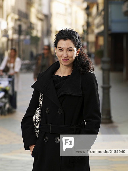 Frau in schwarzem Mantel auf der Straße stehend  lächelnd  Portrait