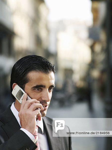 Young businessman using mobile phone in street  close-up