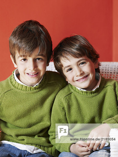 Zwei Brüder (5-7) sitzen lächelnd zusammen  Porträt