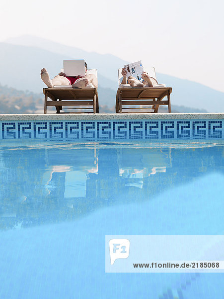 Paar Sonnenbaden am Schwimmbad  Mann mit Laptop