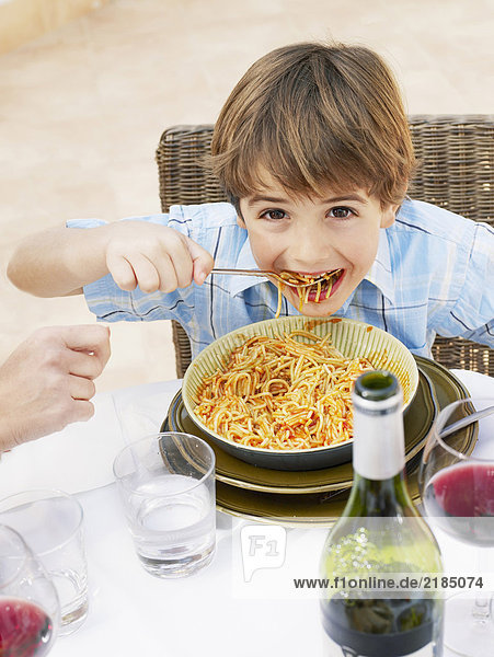 Junge (4-6) isst Spaghetti  lächelnd  Portrait