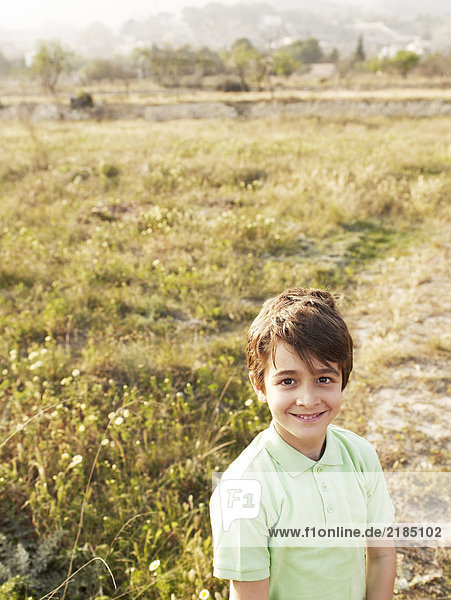 Junge (6-8) im Feld stehend  lächelnd  Portrait