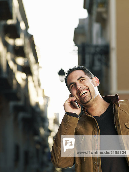 Young man using mobile phone in street  smiling