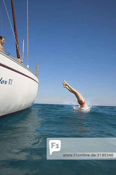 Young woman diving off yacht into sea