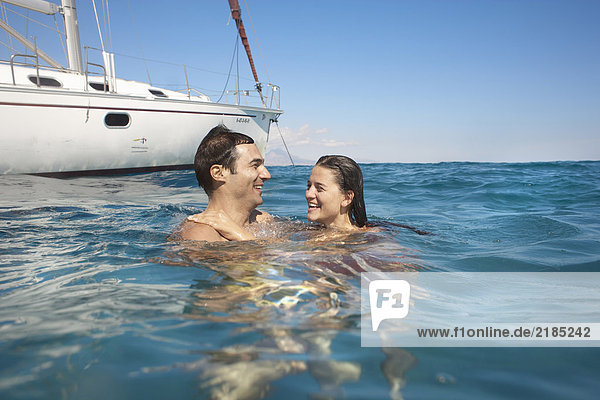Junges Paar  das mit einer Yacht im Meer schwimmt  lächelnd