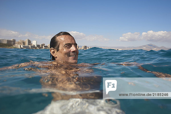 Reifer Mann im Meer schwimmend  lächelnd