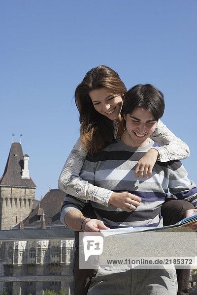 Ein Paar schaut auf eine Karte im Freien und lächelt.