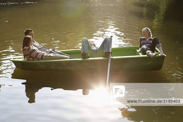 Vier Freunde in einem Ruderboot lächelnd und entspannend.
