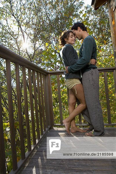 Couple outdoors on balcony being affectionate smiling.