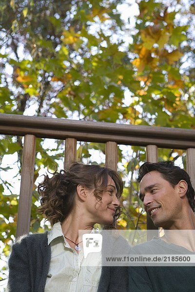 Paar im Freien auf dem Balkon sitzen und lächeln.