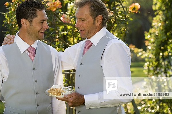 Reifer Vater und Bräutigam sprechen im Garten  lächelnd