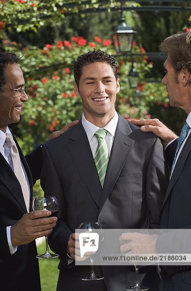 Drei Geschäftsleute trinken Wein in einem Garten