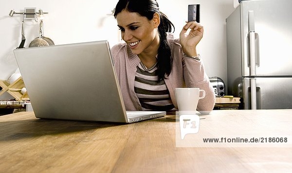Woman looking at laptop with credit card.