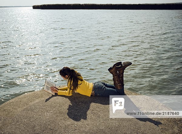 Mädchen am See sitzend.