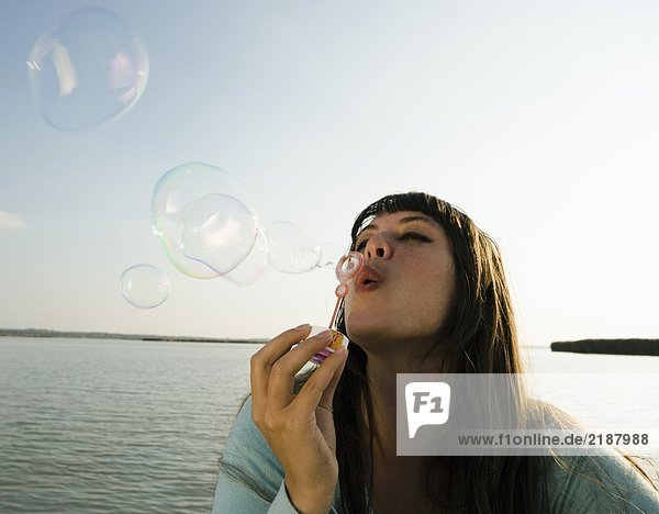 Mädchen bläst Blasen am See.