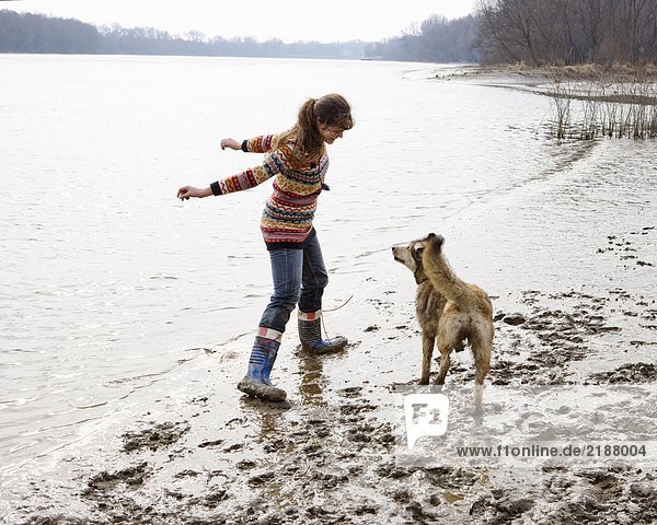 Young woman playing with dog by river