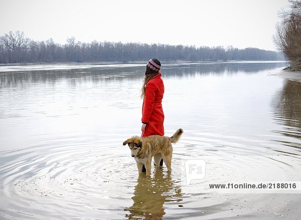 Junge Frau im Fluss stehend mit Hund umgeben von Wellen
