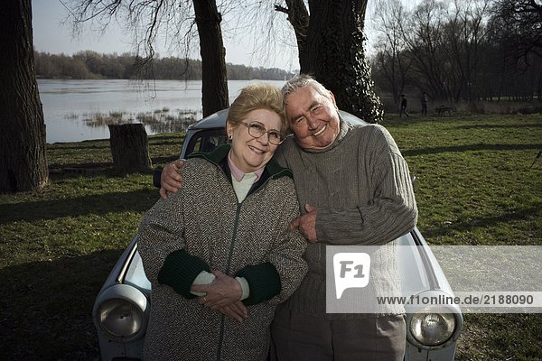 Senior couple leaning on car by riverside  smiling  portrait