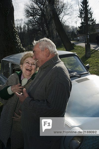 Senior couple leaning on car in countryside  laughing